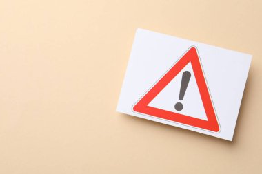 Risk. Bej arka planda uyarı işareti olan bir sayfa kağıt, üst görünüm. Metin için boşluk