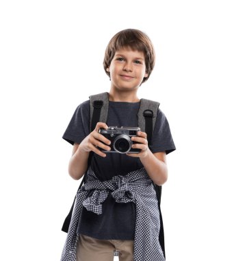 Meslek seçimi. Kameralı ve sırt çantalı küçük çocuk beyaz arka planda fotoğrafçı gibi davranıyor.