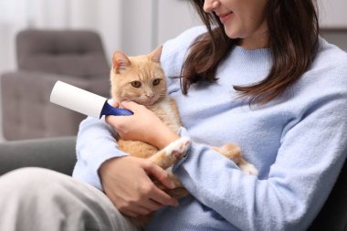 Tiftik silindirli kadın ve kedisi evdeki kanepede, yakın plan.