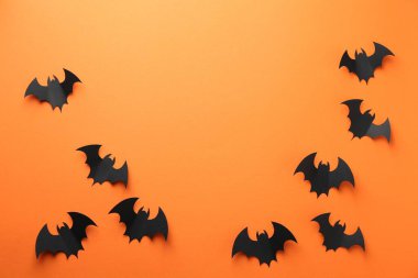 Cadılar Bayramı dekoru. Siyah kağıt yarasalar turuncu arka planda, düz yerde. Metin için boşluk