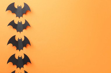 Cadılar Bayramı dekoru. Siyah kağıt yarasalar turuncu arka planda, düz yerde. Metin için boşluk