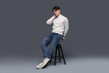 Gri arka planda, kotlu, şık bir adam.