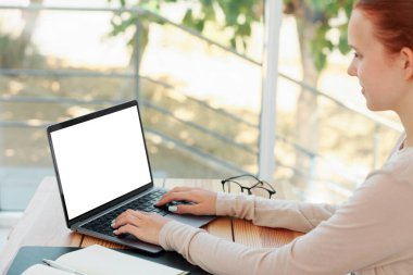 Genç kız odadaki masada dizüstü bilgisayar kullanıyor. Rahat ev işyeri