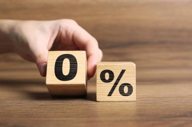 Komisyon yok. Kadın küpü bir diğerinin yanına koyuyor. Tahta masa üzerinde yüzde işareti var. Yakın plan.