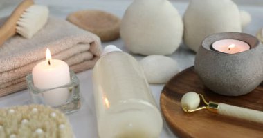Spa ürünleri ve beyaz mermer masada mum yakma kompozisyonu, yakın çekim. Kamera sağa hareket ediyor