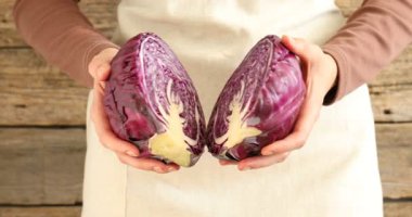 Ahşap arka planda taze olgun lahana yarımları olan kadın, yakın plan.