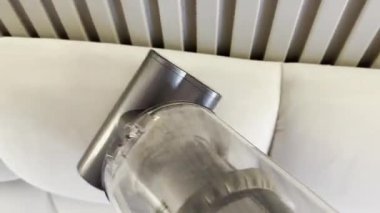 Yatak odasında elektrikli süpürgeyle yatak başlığını temizlemek, yakın çekim.