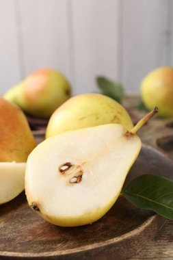 Whole and cut fresh pears on wooden table, closeup