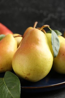 Birçok taze armut ve yaprak siyah masada, yakın plan