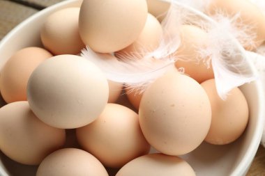 Çiğ tavuk yumurtası ve tüyler masada, yakın plan.