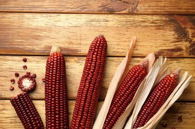 Olgun kırmızı mısır koçanları tahta masada, düz yatıyordu.