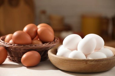 Tabakta çiğ tavuk yumurtası, mutfakta beyaz masada hasır sepet, yakın plan.