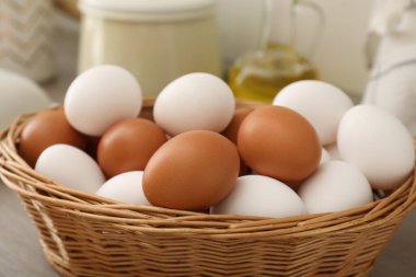 Hasır sepetteki çiğ tavuk yumurtaları ahşap tezgahta, yakın plan.