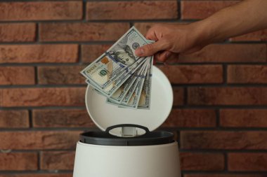 Tuğla duvarın yanındaki çöp kutusuna para atan adam, yakın plan.