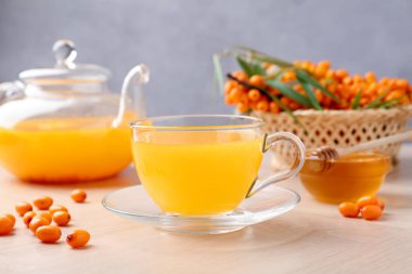 Cam fincanda deniz dikenli çay, çaydanlık, taze böğürtlen ve bal ahşap masada, yakın plan.