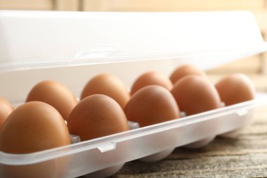 Ahşap masadaki kabın içinde çiğ tavuk yumurtası, yakın plan.