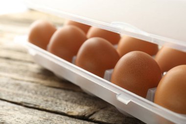 Ahşap masadaki kabın içinde çiğ tavuk yumurtası, yakın plan.