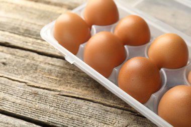 Ahşap masadaki kabın içinde çiğ tavuk yumurtası, yakın plan.