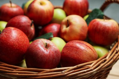 Taze elma ve yeşil yapraklar sepette, yakın plan.