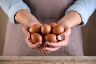 Ahşap masada çiğ tavuk yumurtalı adam, yakın plan.