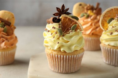 Gri masada renkli kremalı, baharatlı ve kurabiyeli enfes kekler.