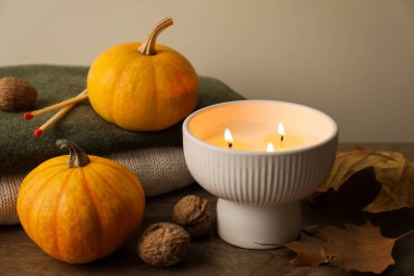 Ahşap masada yanan mum ve balkabaklarıyla sonbahar kompozisyonu