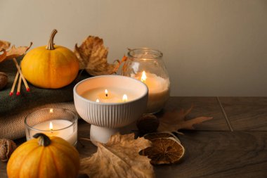 Ahşap masada yanan mumlar ve balkabaklarıyla sonbahar kompozisyonu, yakın plan. Metin için boşluk