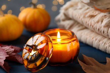 Mavi ahşap masada yanan mum ile sonbahar kompozisyonu bulanık ışıklara karşı, yakın çekim