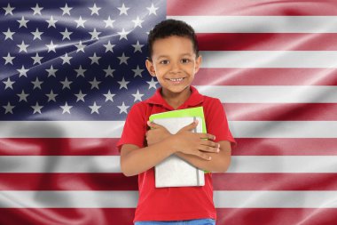 Amerikan bayrağına karşı defterleri olan küçük bir çocuk. Dil okulu