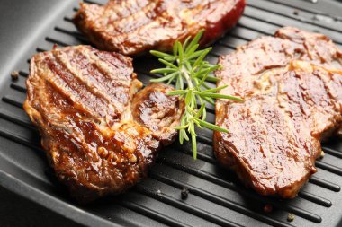 Izgara biftek, biberiye ve siyah tavada biberiye, yakın plan.