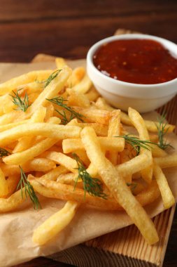 Tasty french fries with sauce on wooden table, closeup