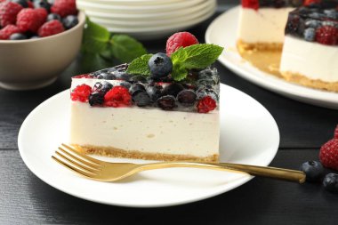 Lezzetli peynirli kek, böğürtlenli ve nane şekerli, siyah ahşap masa, yakın plan.