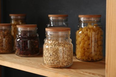 Ahşap rafta farklı ürünler bulunan cam kavanozlar, yakın plan.