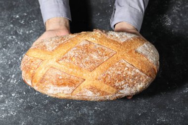 Gri desenli masada bir somun taze ekmekle fırıncı.