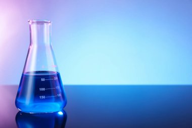 Ayna yüzeyinde mavi sıvı bulunan cam matara renk arkaplanı, metin için boşluk