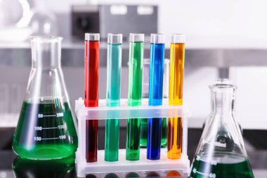 Test tüpleri ve diğer farklı renkte sıvılarla laboratuvar masasında, yakın plan.