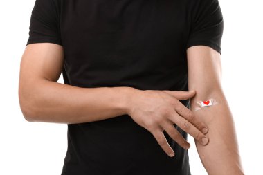 Kan bağışı. Kolu beyaz arkaplanda bandajlı adam, yakın plan.