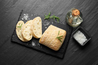 Kesilmiş ciabatta, biberiye, siyah desenli masa üzerinde tuz ve yağ, düz yatıyordu.