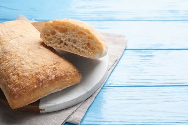 Açık mavi ahşap masada taze çıtır ciabatalar, yakın plan. Metin için boşluk