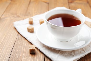 Aromatik siyah çay bardakta ve şeker küpleri ahşap masada, yakın plan. Metin için boşluk