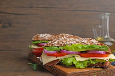 Peynirli ve sebzeli lezzetli ciabatta sandviçler ahşap masada, yakın plan. Metin için boşluk