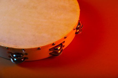 Kırmızı arka planda tef, yakın plan. Geleneksel müzik aleti