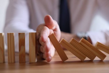 Risk. Tahta masada domino efektini durduran adam, yakın plan.