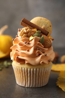 Renkli kremalı, tarçınlı, kurabiyeli, fındıklı ve sonbahar desenli kek gri masada, yakın plan.