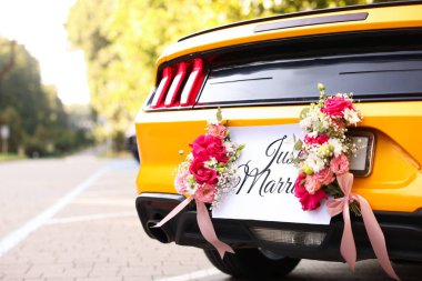 Düğün arabası. Cabriolet dekore edilmiş. Sadece evlilik kartı ve açık havada güzel çiçekler, yakın plan.