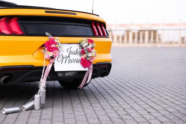 Düğün arabası. Cabriolet, Yeni Evli kartıyla dekore edilmiş, güzel çiçekler ve teneke kutular, yakın plan. Metin için boşluk