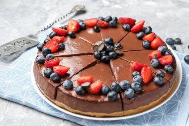 Açık gri desenli masada böğürtlenli çikolatalı kek, yakın plan.