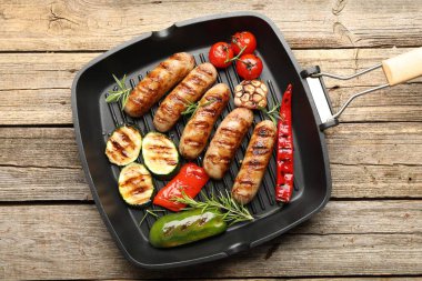 Tavada ızgara sosis, sebze ve baharat, ahşap masa, üst manzara.