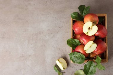 Gri masadaki ahşap sandıkta yeşil yapraklı taze elmalar, üst manzara. Metin için boşluk