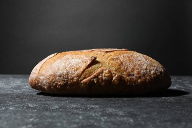 Gri desenli masada bir somun taze ekmek, yakın plan.